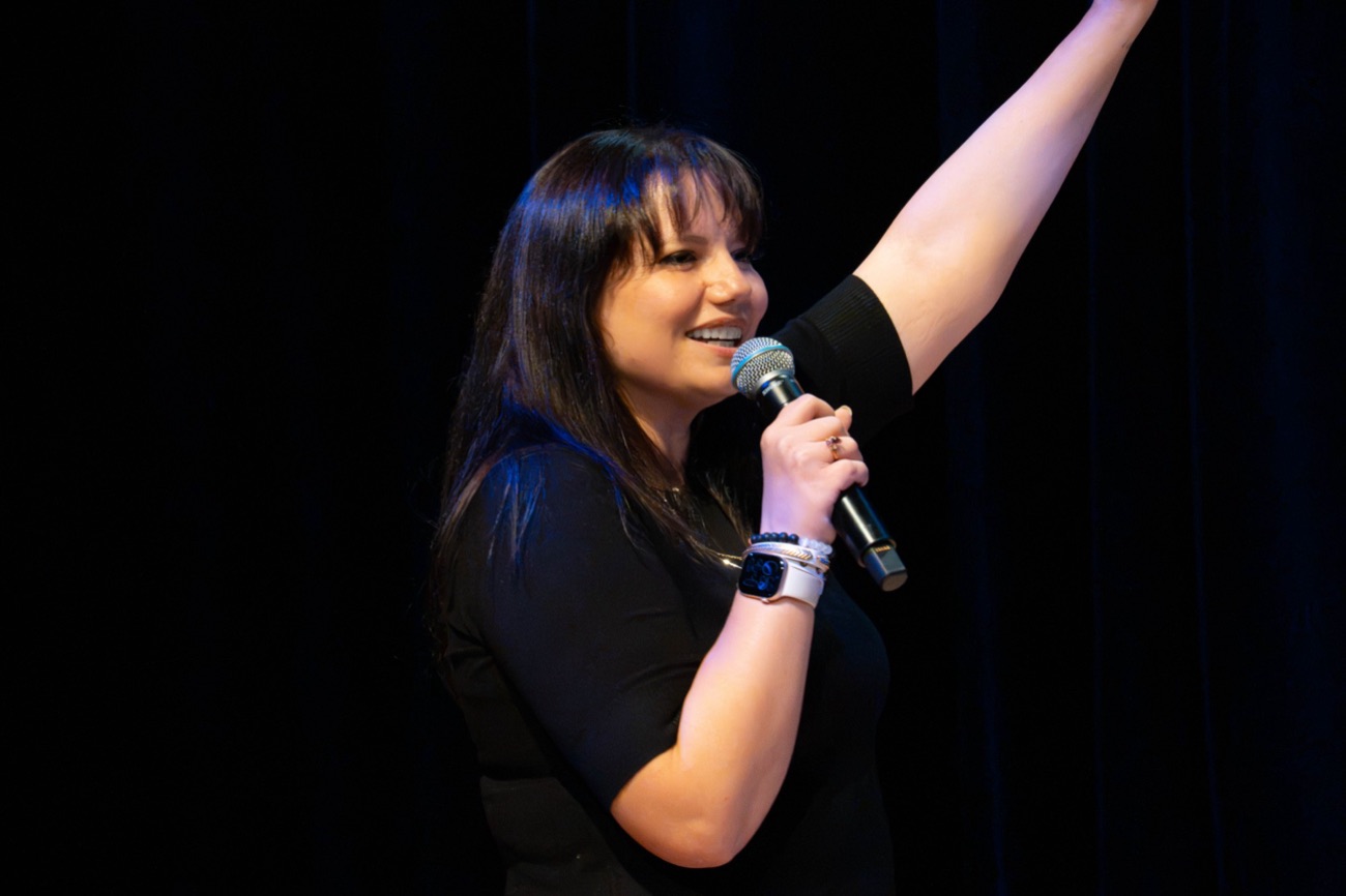 Brooke on stage with a microphone and one arm raised